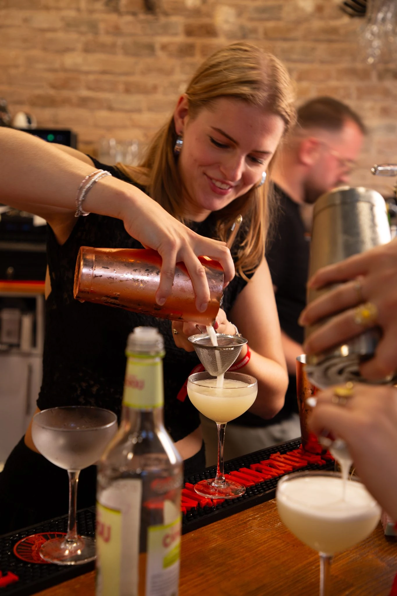 cocktail-wordt-door-een-deelnemer-gezeefd-in-een-coupeglas-tijdens-de-workshop