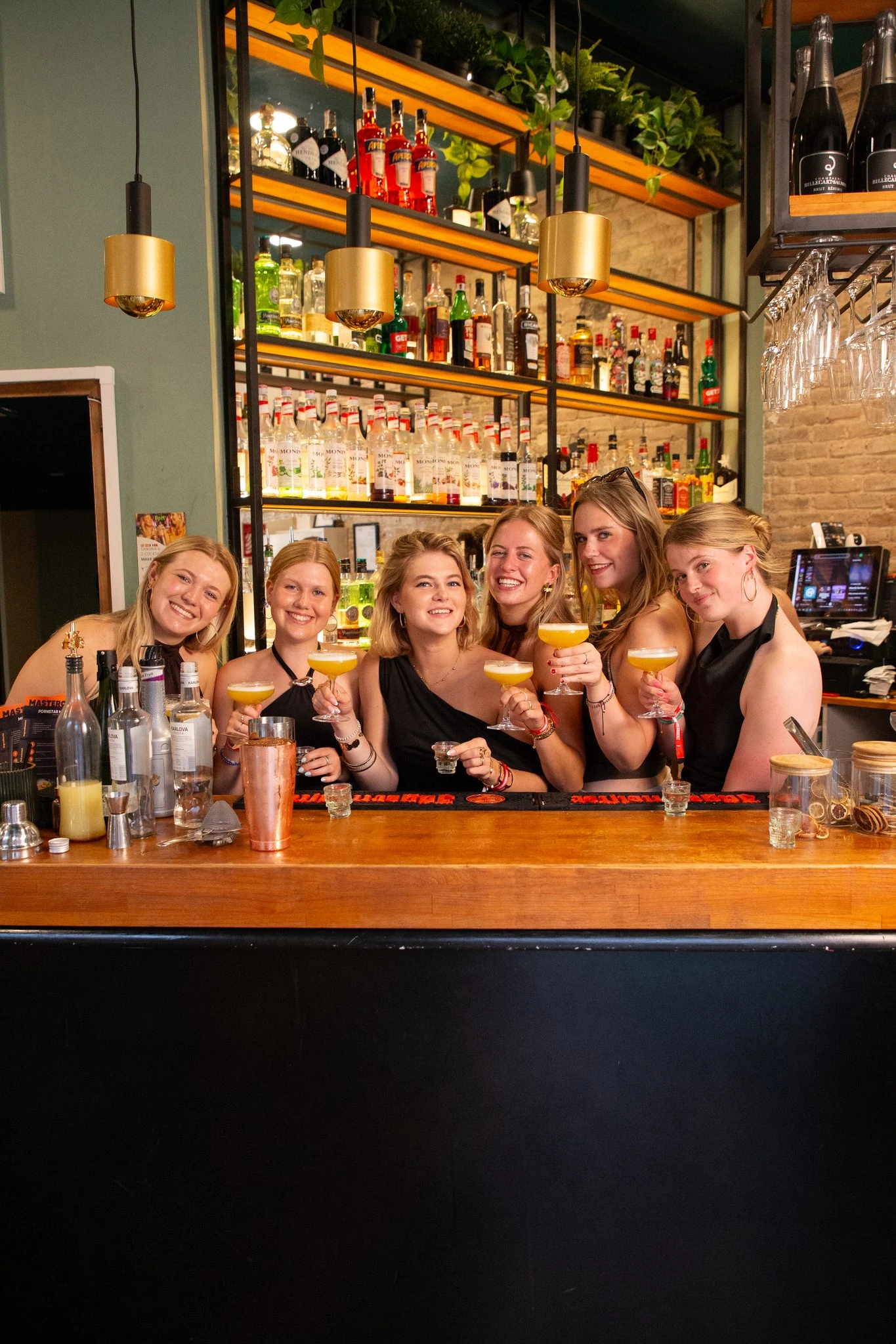 groep-poseert-met-cocktails-achter-de-bar-bij-bpm-bar-eixample-in-barcelona